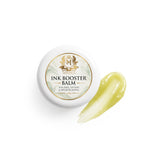 Skin Monarch Ink Booster Balm 30ml, lid beside a glossy yellow balm smear